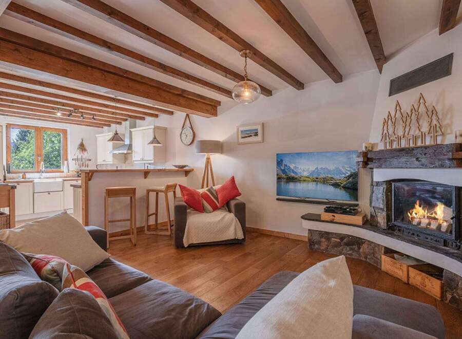 Experience the warmth and charm of this cozy living space, featuring a stunning fireplace and exposed wooden beams.