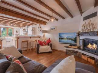 Experience the warmth and charm of this cozy living space, featuring a stunning fireplace and exposed wooden beams.