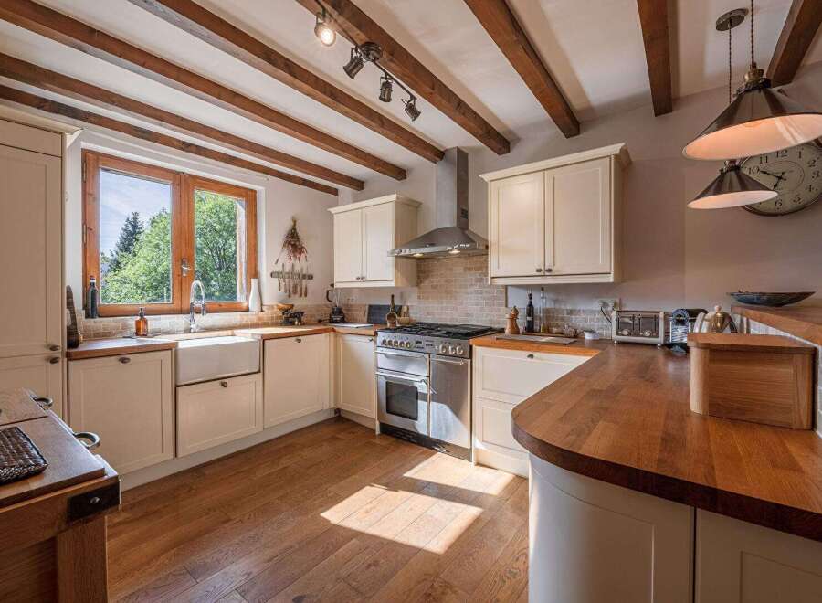 This stunning kitchen boasts a warm and inviting atmosphere with its exposed wooden beams and natural light.