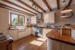 This stunning kitchen boasts a warm and inviting atmosphere with its exposed wooden beams and natural light.