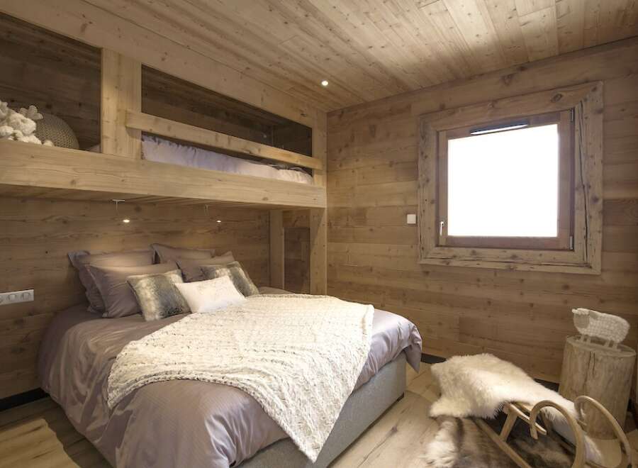This cozy bedroom features a unique bunk bed design with wooden paneling throughout, creating a warm and inviting atmosphere.