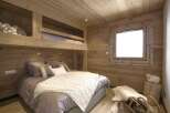 This cozy bedroom features a unique bunk bed design with wooden paneling throughout, creating a warm and inviting atmosphere.