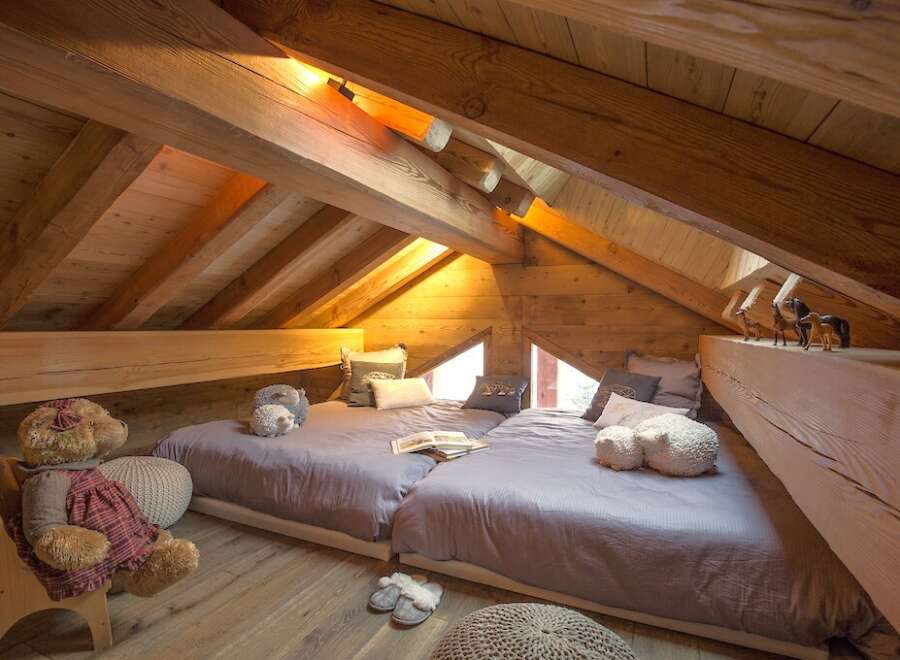 This cozy attic bedroom features a unique design with exposed wooden beams and a charming, rustic aesthetic.