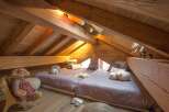 This cozy attic bedroom features a unique design with exposed wooden beams and a charming, rustic aesthetic.