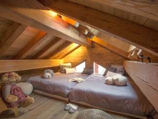 This cozy attic bedroom features a unique design with exposed wooden beams and a charming, rustic aesthetic.