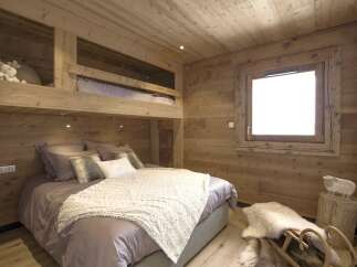 This cozy bedroom features a unique bunk bed design with wooden paneling throughout, creating a warm and inviting atmosphere.