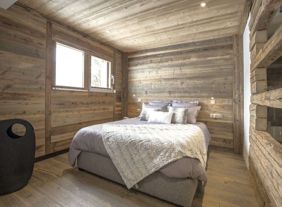 This cozy bedroom features rustic wooden walls and ceiling, creating a warm and inviting atmosphere.