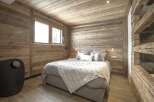 This cozy bedroom features rustic wooden walls and ceiling, creating a warm and inviting atmosphere.