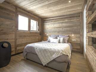 This cozy bedroom features rustic wooden walls and ceiling, creating a warm and inviting atmosphere.
