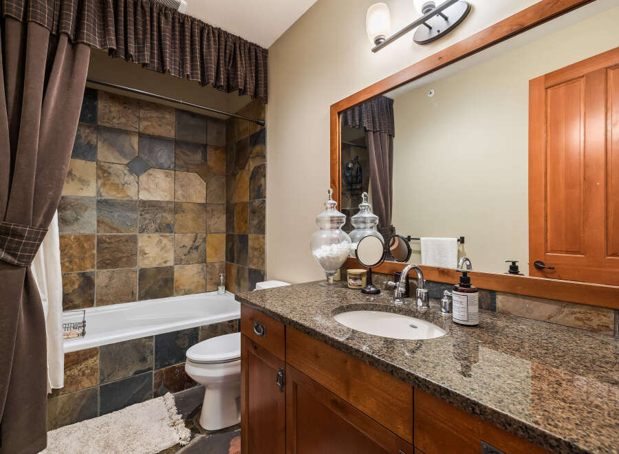 This stunning bathroom boasts a luxurious design with a beautiful stone tile shower and a granite countertop vanity.