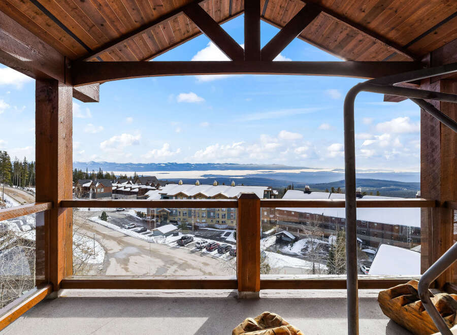 Enjoy breathtaking views from this stunning property, featuring a spacious balcony with a wooden frame.