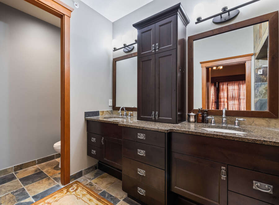 This luxurious bathroom boasts a stunning dark wood vanity with ample storage, complemented by a beautiful granite countertop.