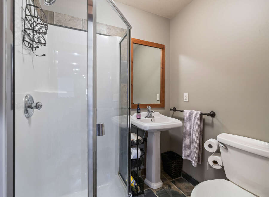 Step into this beautifully designed bathroom, featuring a modern shower and a stylish pedestal sink.