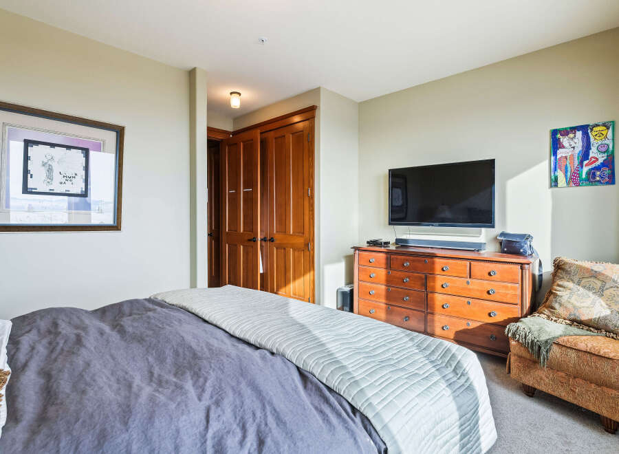 Step into this inviting bedroom, featuring a comfortable bed with a stylish gray duvet and a cozy armchair.