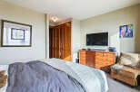 Step into this inviting bedroom, featuring a comfortable bed with a stylish gray duvet and a cozy armchair.