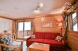 Discover the charm of this cozy living space, featuring a vibrant red sofa and rustic wooden accents.