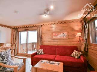 Discover the charm of this cozy living space, featuring a vibrant red sofa and rustic wooden accents.