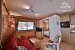 Discover the charm of this cozy apartment, featuring a warm wooden interior and a comfortable red sofa.