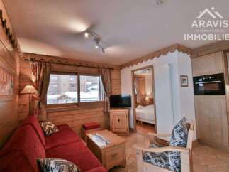Discover the charm of this cozy apartment, featuring a warm wooden interior and a comfortable red sofa.