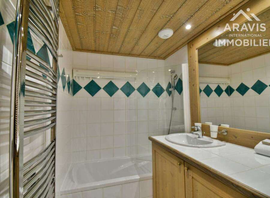 This charming bathroom features a stylish design with a wooden ceiling and a modern sink.