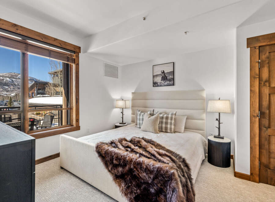 This luxurious bedroom features a cozy ambiance with a plush bed and a warm, inviting fur throw.