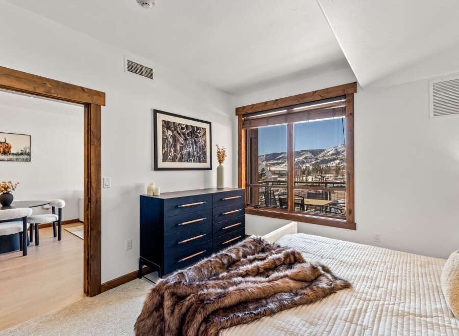 This stunning bedroom boasts a luxurious ambiance with its plush fur throw and elegant dark wood dresser.