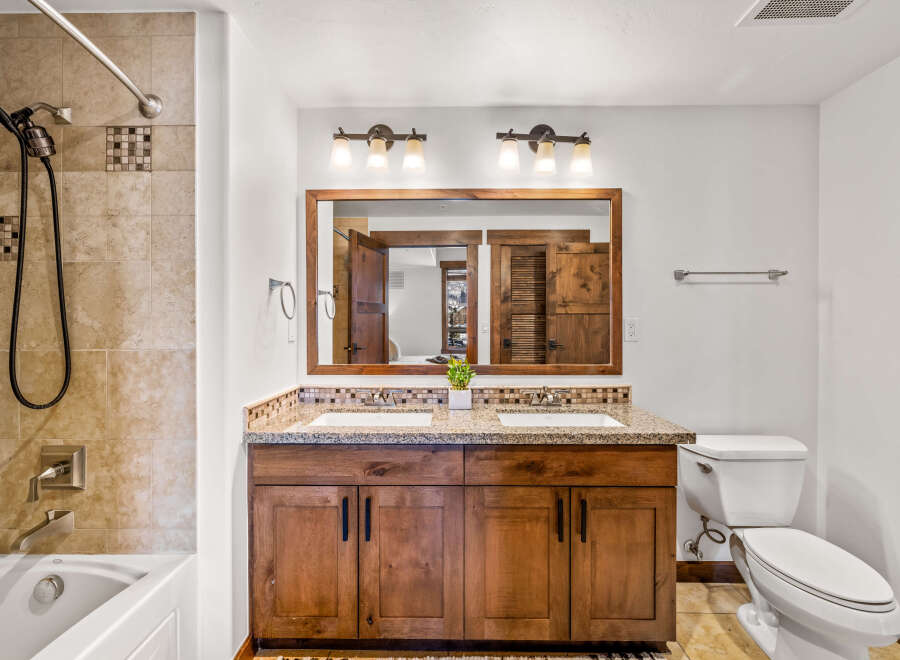 This stunning bathroom boasts a luxurious double vanity with a granite countertop and elegant wooden cabinetry.