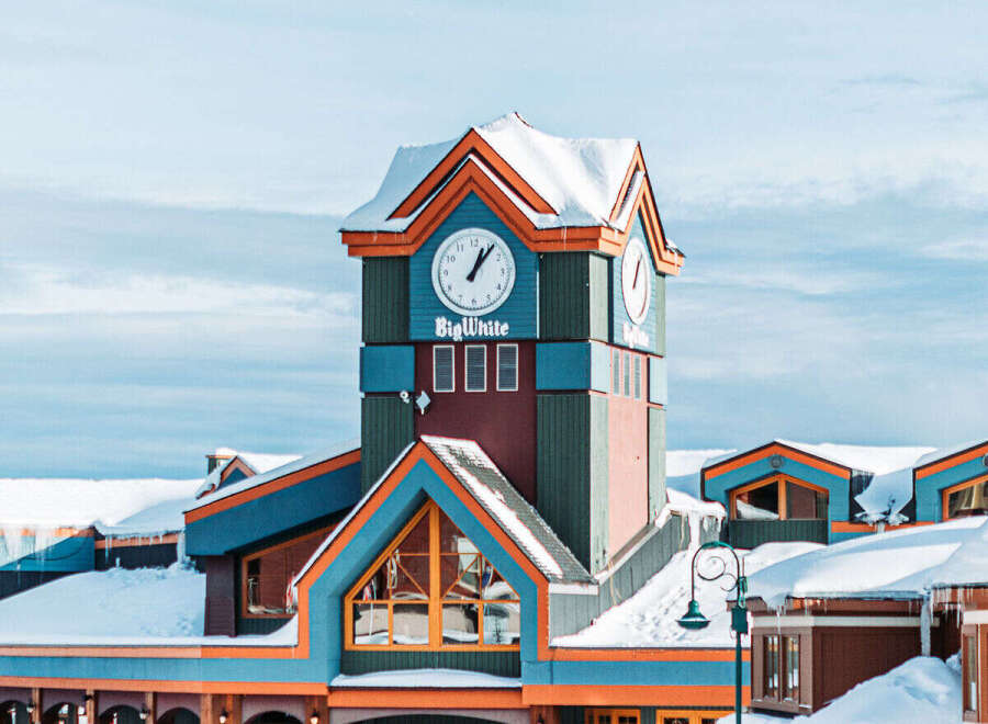 Discover the charm of Big White Ski Resort! This stunning property boasts a unique architectural design with vibrant colors and a clock tower, creating a picturesque winter wonderland.