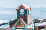 Discover the charm of Big White Ski Resort! This stunning property boasts a unique architectural design with vibrant colors and a clock tower, creating a picturesque winter wonderland.