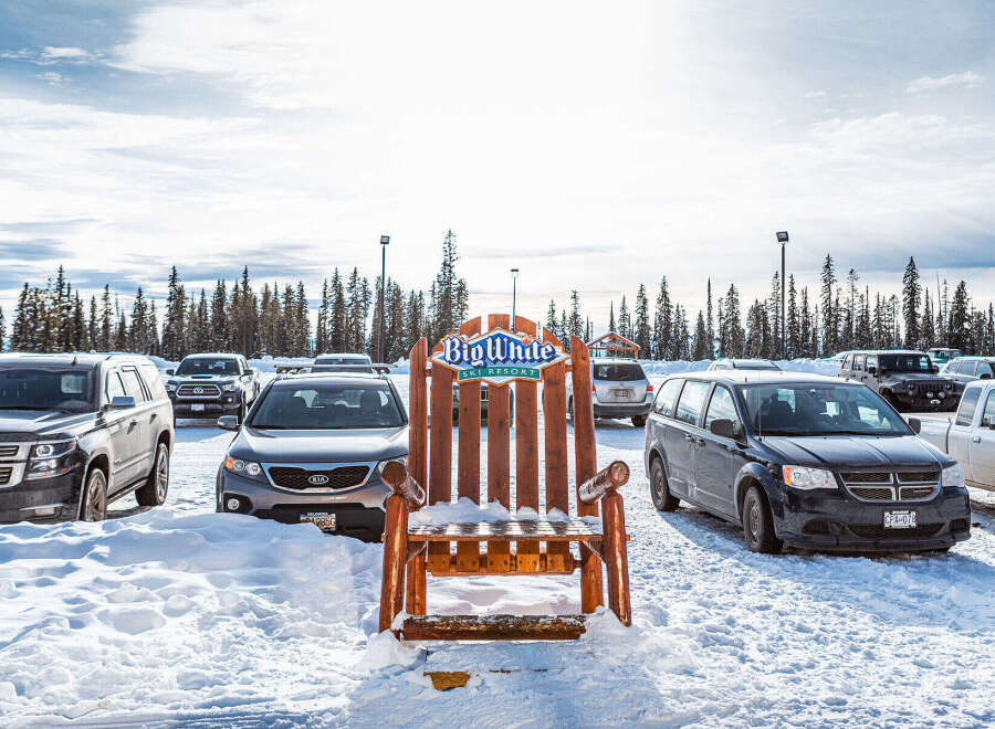 Explore the winter wonderland at Big White Ski Resort! This stunning property offers a unique experience with its charming wooden chair and ample parking.