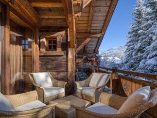 Enjoy the serene beauty of this stunning chalet, complete with a cozy outdoor seating area.