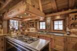 This stunning kitchen showcases rustic charm with its warm wooden cabinetry and exposed beams, creating a cozy and inviting atmosphere.