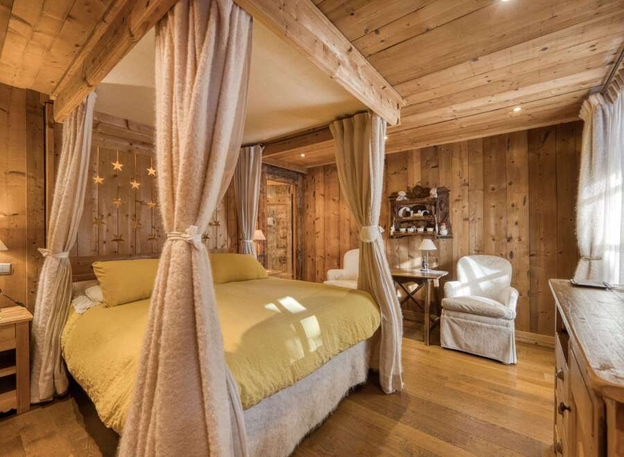 Step into a cozy bedroom retreat, featuring a charming four-poster bed draped with soft, flowing curtains.