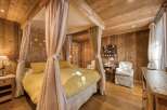 Step into a cozy bedroom retreat, featuring a charming four-poster bed draped with soft, flowing curtains.