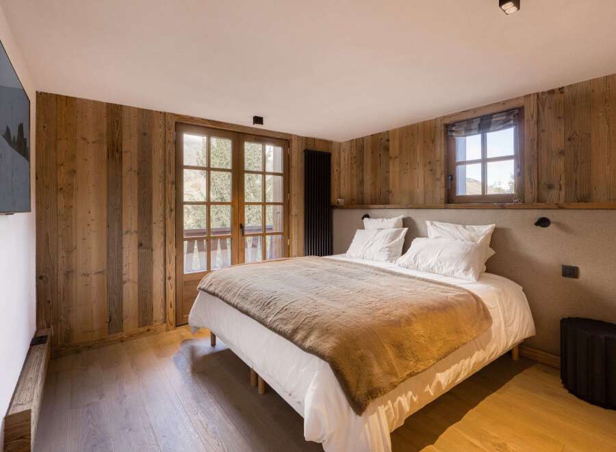 This cozy bedroom features rustic wooden walls and a comfortable bed, creating a warm and inviting atmosphere.