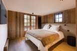 This cozy bedroom features rustic wooden walls and a comfortable bed, creating a warm and inviting atmosphere.