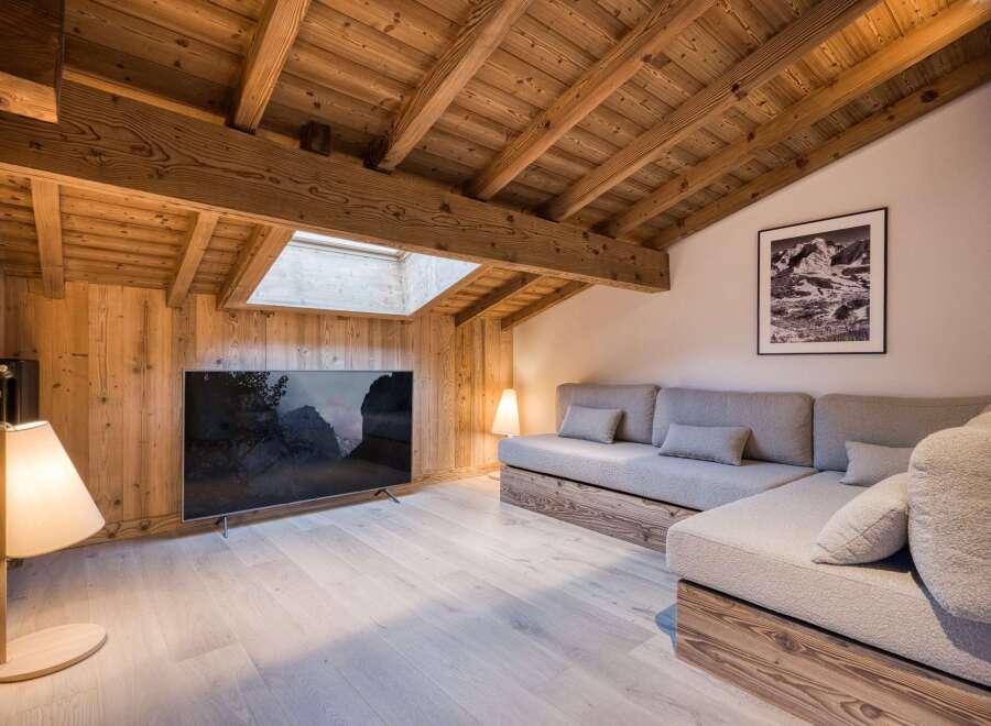This stunning living space boasts a cozy, rustic charm with its wooden beamed ceiling and walls.