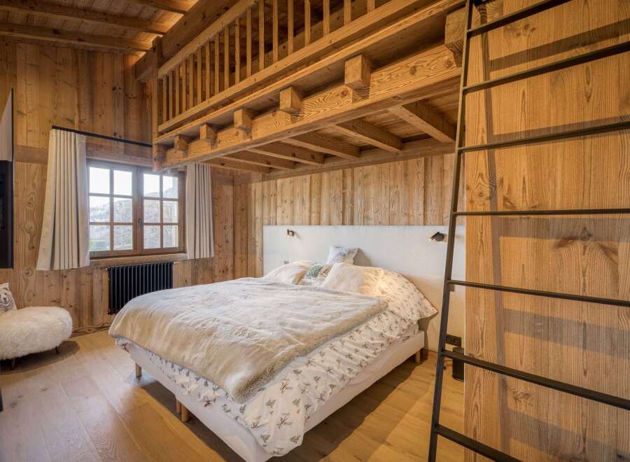 Experience rustic charm in this stunning bedroom featuring warm wooden accents and a cozy ambiance.