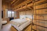 Experience rustic charm in this stunning bedroom featuring warm wooden accents and a cozy ambiance.
