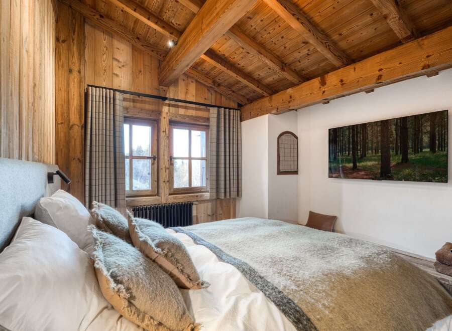 Experience rustic charm in this cozy bedroom, featuring stunning wood paneling and a vaulted ceiling.