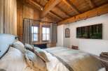 Experience rustic charm in this cozy bedroom, featuring stunning wood paneling and a vaulted ceiling.