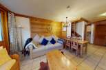 Discover the charm of this cozy living space, featuring a comfortable sofa and a rustic wooden dining table.