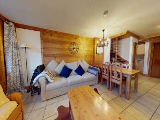 Discover the charm of this cozy living space, featuring a comfortable sofa and a rustic wooden dining table.