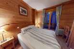 Step into this cozy bedroom featuring beautiful wood paneling and a comfortable bed with striped bedding.