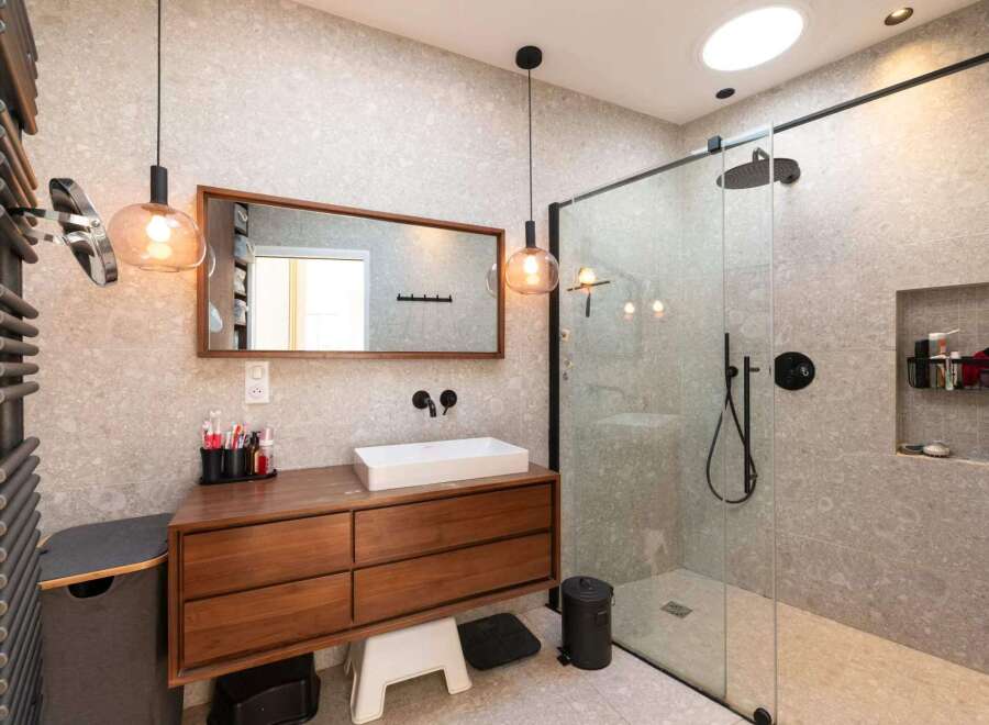 This modern bathroom boasts a sleek design with a wooden vanity and a frameless glass shower.