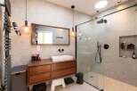 This modern bathroom boasts a sleek design with a wooden vanity and a frameless glass shower.