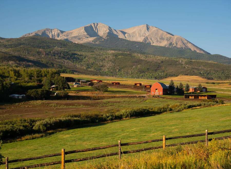 Nestled in a picturesque landscape, this stunning property boasts a charming red barn and expansive green fields.