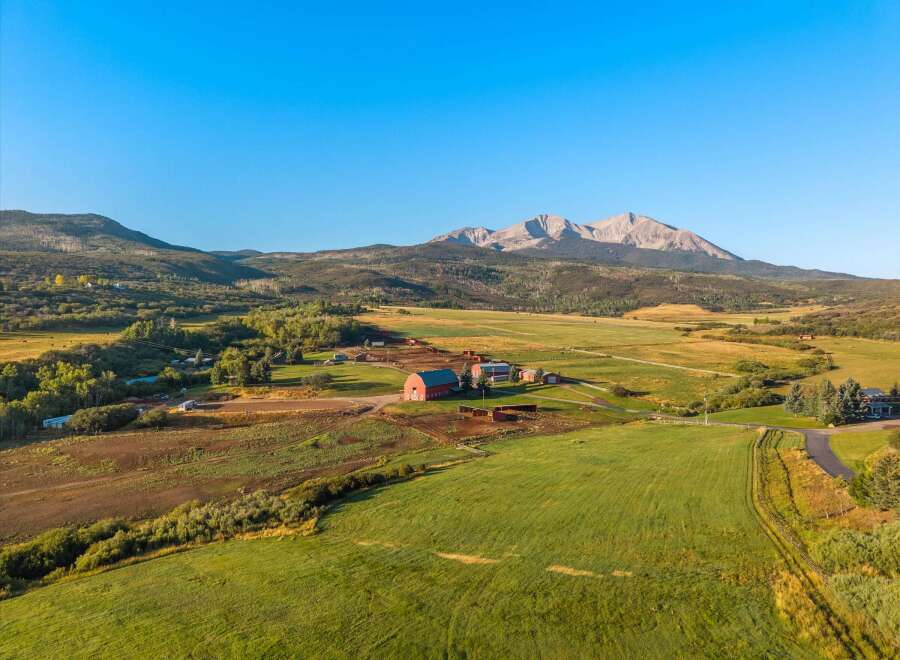 Discover the tranquility of this stunning rural property, featuring a picturesque red barn and expansive green fields.