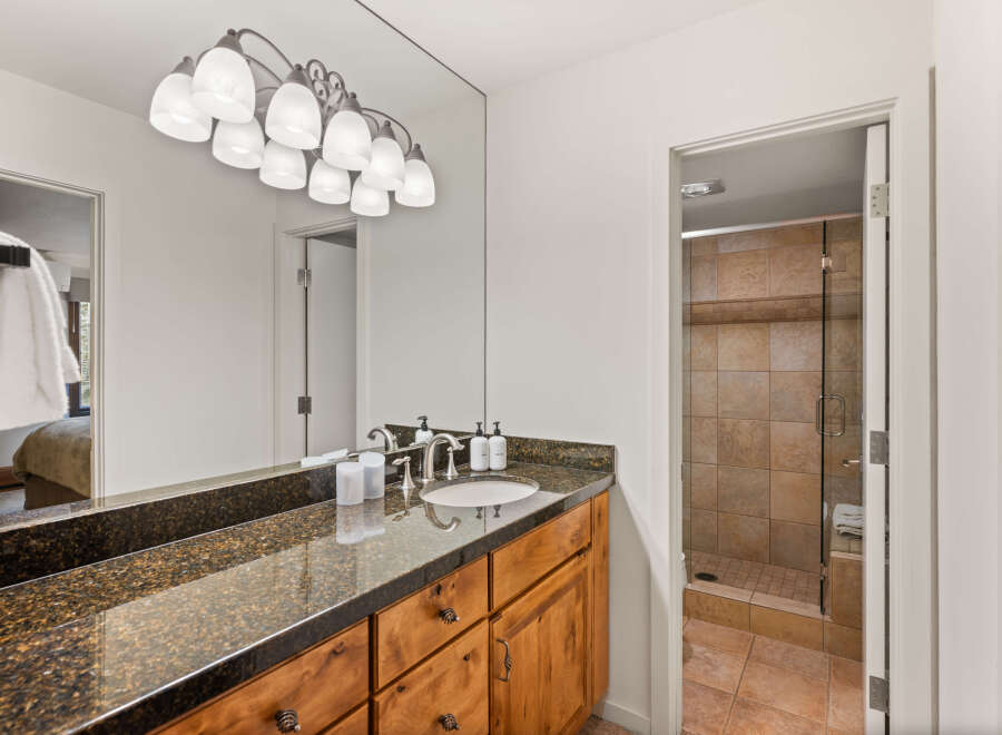 This stunning bathroom features a sleek granite countertop and custom wooden cabinetry, offering both style and functionality.
