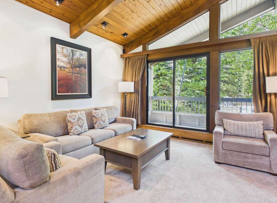 Experience mountain living in this cozy living room featuring a plush sectional sofa and a comfortable armchair, perfect for relaxing after a day of adventure.